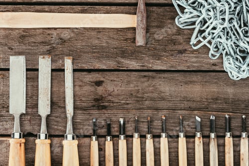 Preview: flat lay with chain, hammer and chisels for woodcraft on dark wooden tabletop