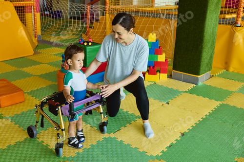 Preview: Cute young boy patient enjoys a session of physical rehabilitation using rehab walker