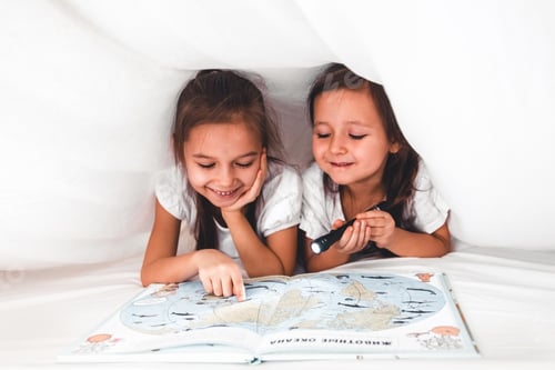Preview: Two Girls Reading a Book Under a Blanket