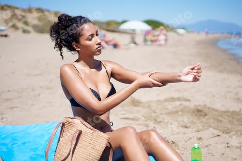 Preview: A woman is applying sunscreen while enjoying the sun on a beautiful beach setting