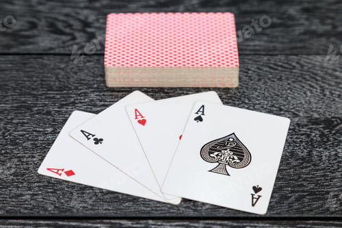 Preview: Four aces and a deck of cards lie on a wooden table