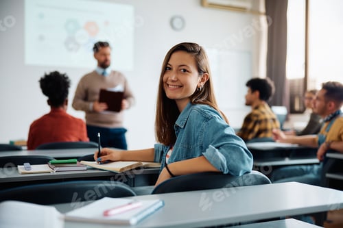 Preview: Happy female student during a class at the university looking at camera.