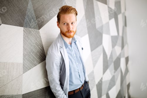 Man in Light Jacket Leaning Against Patterned Wall