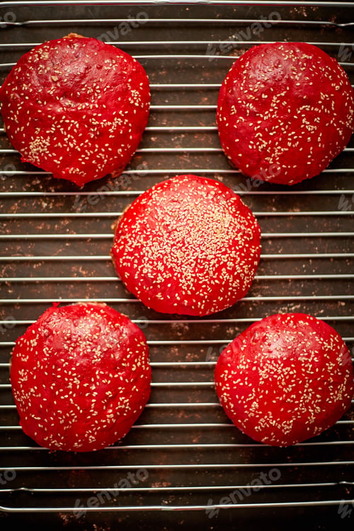 Preview: Fresh baked red homemade burger buns with sesame top view. Placed on metal grill