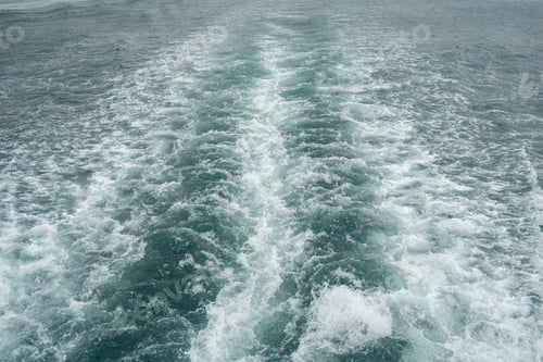 Preview: Rippling waves create dynamic patterns behind a boat as it moves through a serene sea under an