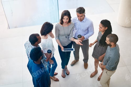 Preview: Pooling their brain power. High angle shot of businesspeople talking in the lobby of their office.
