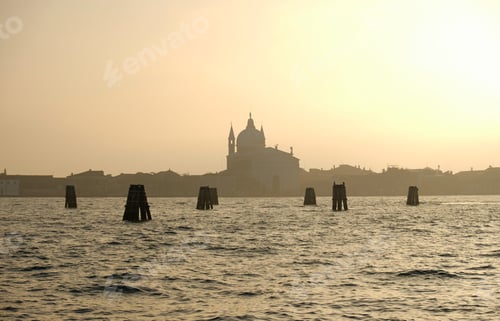 Preview: Misty sunset or sunrise over Venetian lagoon with silhouette of historic church.
