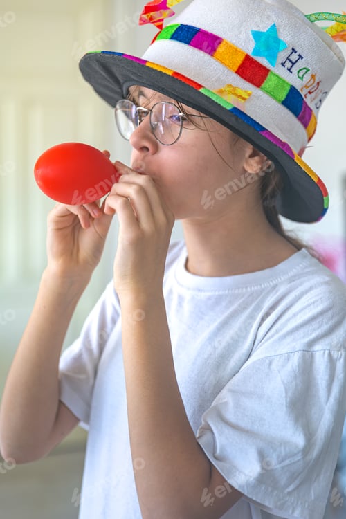Preview: A festive girl inflates a balloon on her birthday. Birthday concept.