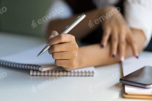 Preview: Close-up of hand holding a pen and a notepad ready to write.