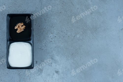 Preview: Honey topped with single walnut and a portion of cream on marble background