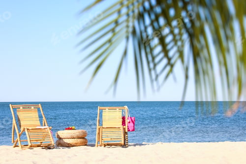 Preview: Empty wooden sunbeds and beach accessories on sandy shore