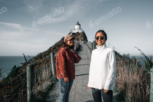 Preview: two caucasian young women standing dressed in white pullover red jacket black and blue pants having