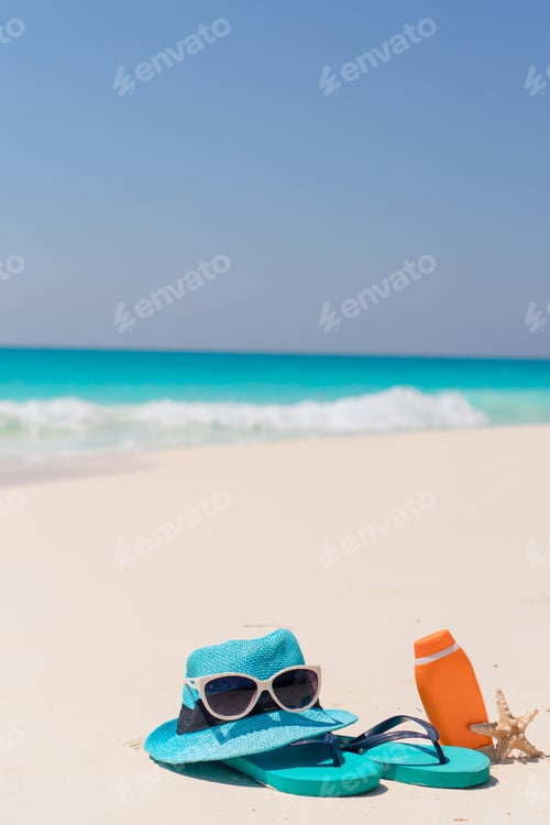 Preview: Suncream bottles, goggles, starfish and sunglasses on white sand beach background ocean