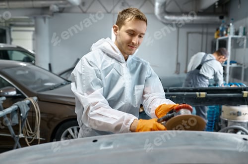 Preview: Serviceman polishing car body part in workshop