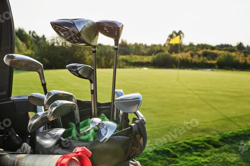 Preview: Metal golf clubs set close-up, over background of a golf course with a flagstick and a beautiful