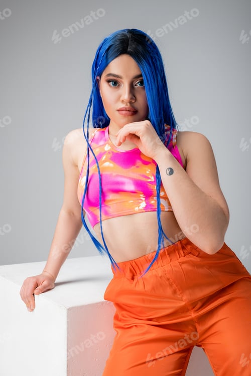 Preview: rebel style, tattooed young woman with blue hair posing in colorful clothes