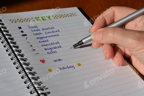 Preview: Woman writing in a bullet journal, close up, pen in hand