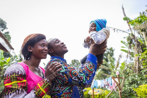 Preview: A father raises his newborn son to the sky with his wife at his side smiling, happy African family