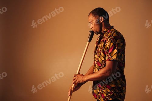 Preview: African american man musician playing the flute at brown background copy space. Online musical