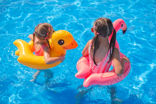 Preview: Two girls with circles in shape of flamingos and duck swim in clear clear water
