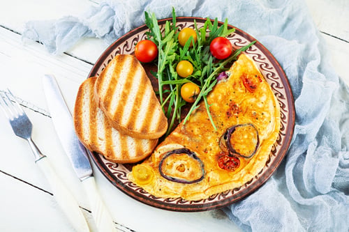 Preview: Omelet with tomato, onion, cheese and herbs. Tasty breakfast omelette. Top view