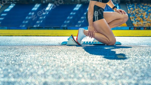 Preview: Side view cropped shot of female runner sitting at the start line on running track