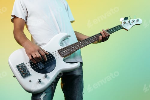 Preview: Close-up photo of man playing white bass guitar on colorful background