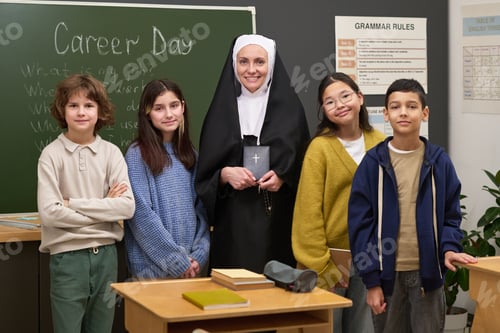 Preview: Portrait of Middle Aged Caucasian Nun Standing with Diverse Schoolchildren
