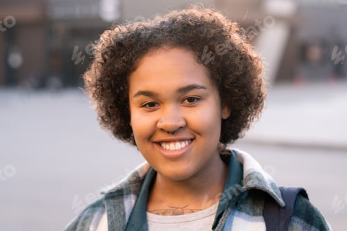 Preview: Happy girl of African ethnicity standing in urban environment