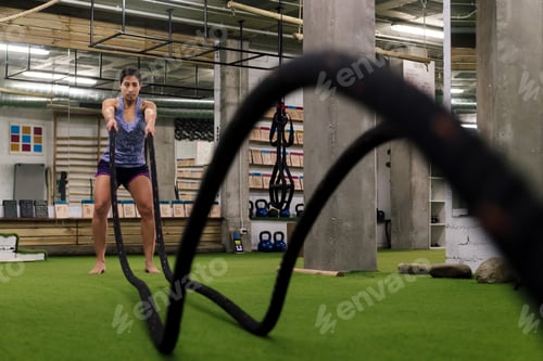 Preview: sportswoman training by shaking the ropes
