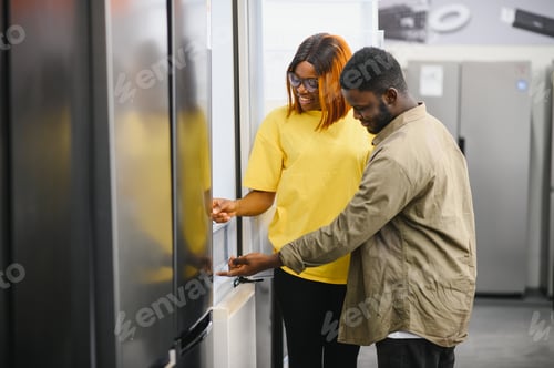 Preview: Young african american man and woman are choosing a fridge in an appliance store.
