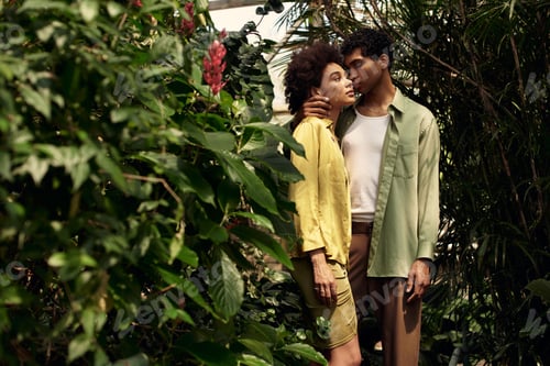 Preview: Young couple shares a romantic moment surrounded by lush greenery in a greenhouse setting