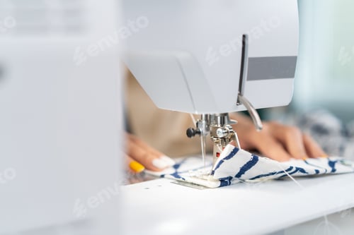 Preview: Close up hands of designer pushes fabric material in sewing machine.