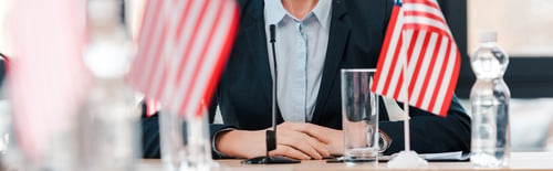 Preview: panoramic shot of businesswoman near american flags on table