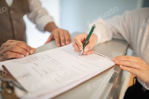 Preview: A person signs a document with a green pen