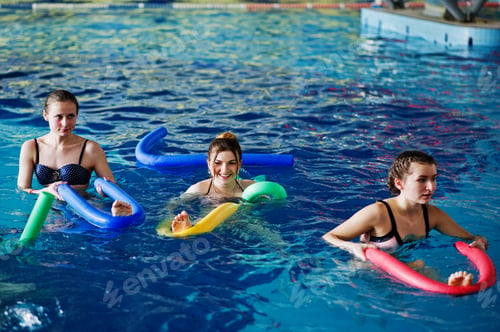 Preview: Fitness group of girls doing aerobical excercises in swimming pool