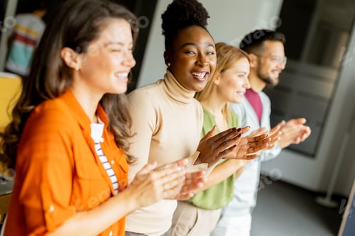 Preview: Young multiethnic startup team standing and applauding in the modern office
