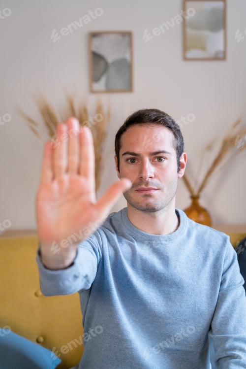 Preview: Man showing stop gesture at home