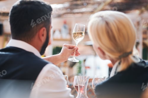 Preview: Two professional cavists studying characteristics of wine sample in flute