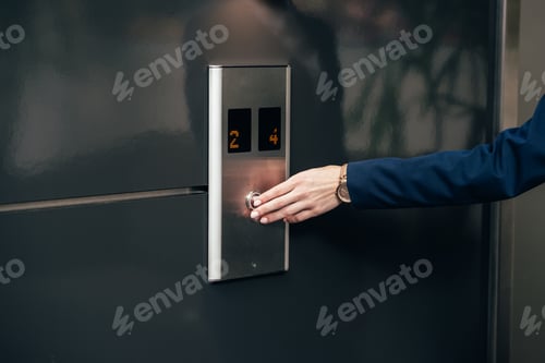 Preview: cropped shot of businesswoman pressing button of elevator