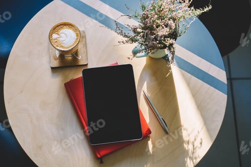 Preview: Table with tablet located on planner and cup of cappuccino near flowers