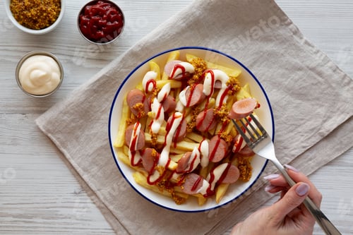 Preview: Homemade Salchipapa Fries with Ketchup, Mustard and Mayo on a Plate, top view.