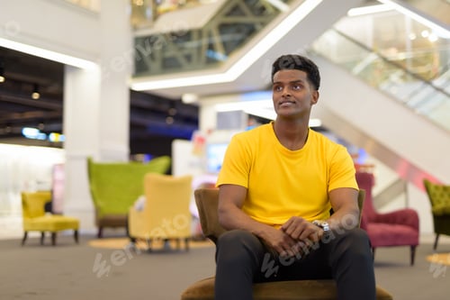 Preview: Portrait of handsome black African man wearing yellow t-shirt while sitting and thinking
