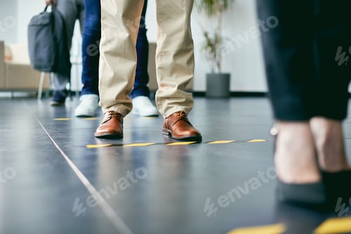 Preview: Close-up of business people standing in a row behind social distance lines.