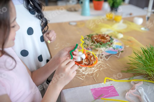 Preview: Picture of easter buns standing on the table and girls hands decorating