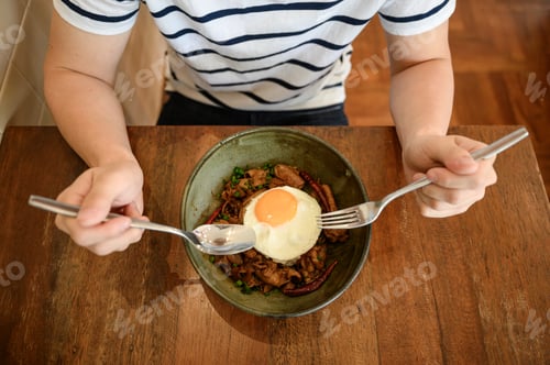 Preview: Man preparing for eating a rice with marinated chili pork and fried egg in ceramic bowl