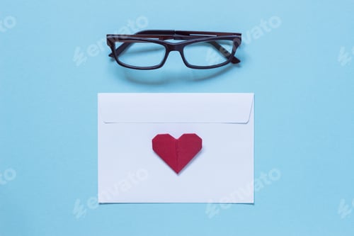 Preview: Eyeglasses, white paper envelope and red origami heart. Work space. Top view. Valentine's Day.