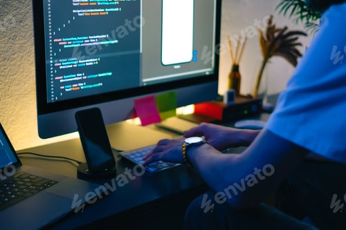Preview: Young man mobile developer writes program code on a computer, programmer work in home office.