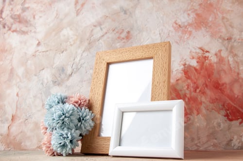 Preview: Close up view of empty wooden photo frames standing on table and flower on nude color background