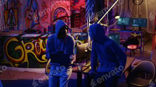 Preview: Hooded Individuals with Laptops in Graffiti Decorated Room